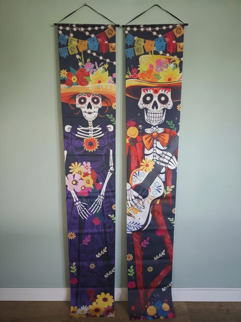 Twee Día de los Muertos banners: een skeletvrouw met bloemen en een skelet met gitaar